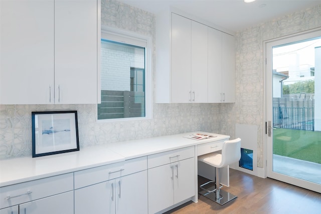 kitchen with backsplash, wood finished floors, white cabinets, and light countertops