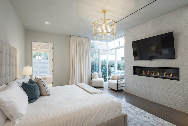 bedroom featuring recessed lighting, a chandelier, a large fireplace, and wood finished floors