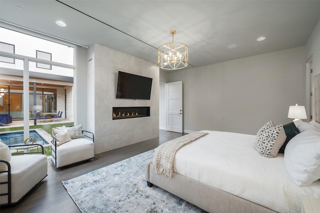 bedroom featuring a chandelier, recessed lighting, a tiled fireplace, and wood finished floors