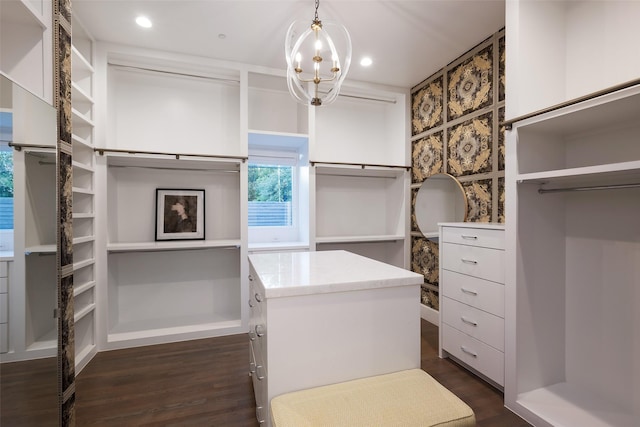 walk in closet with an inviting chandelier and dark wood finished floors