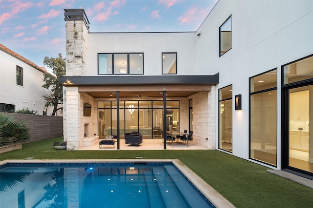 rear view of house with a ceiling fan, a patio, fence, a yard, and a fenced in pool