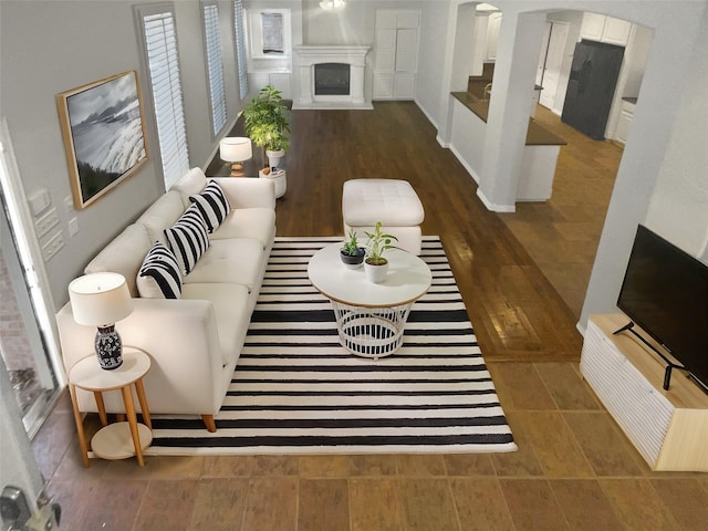 living area with wood finished floors, a fireplace, and arched walkways