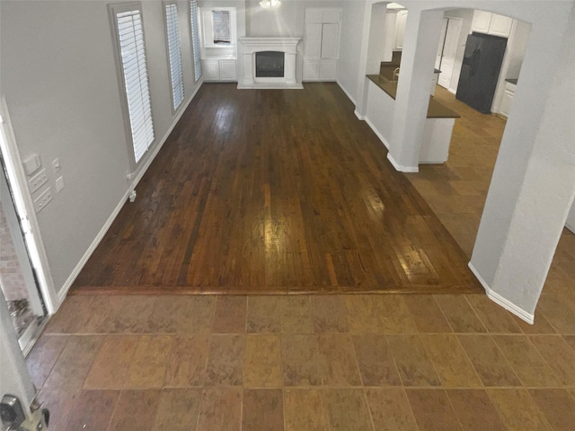 corridor featuring dark wood-style floors, arched walkways, and baseboards