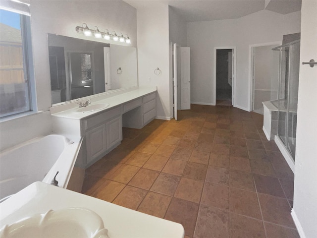 bathroom featuring a garden tub, a stall shower, vanity, and baseboards