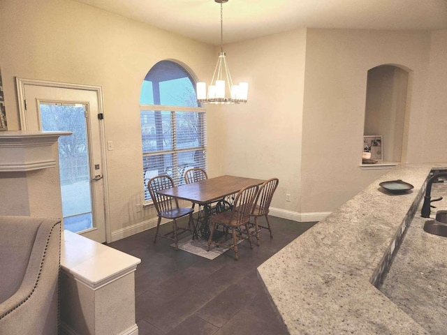 dining space featuring baseboards, an inviting chandelier, and dark wood-style flooring