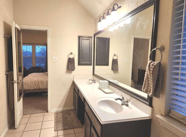 bathroom featuring tile patterned flooring, connected bathroom, lofted ceiling, and a sink