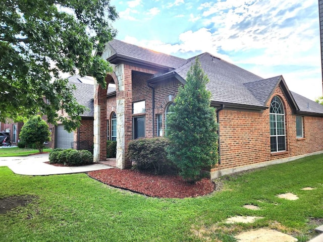 view of side of home with brick siding, an attached garage, driveway, and a shingled roof