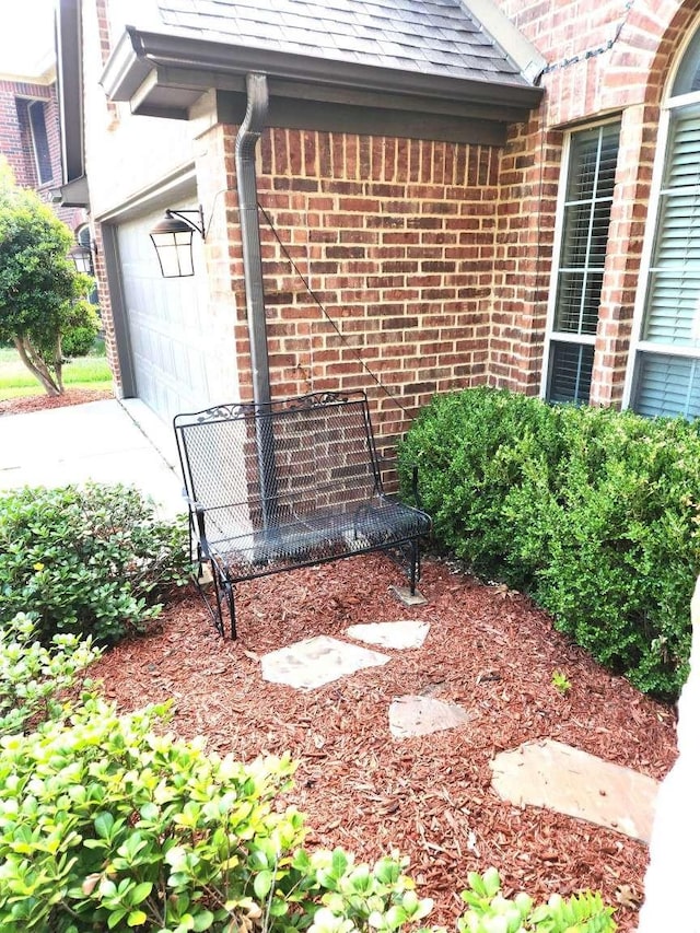 exterior space with a garage, brick siding, roof with shingles, and driveway