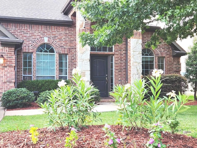 doorway to property with brick siding and roof with shingles