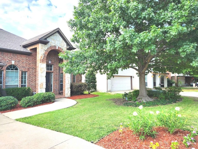 view of front of home featuring roof with shingles, a front lawn, a garage, stone siding, and brick siding