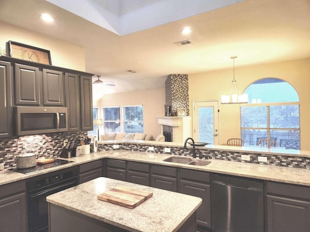 kitchen with light stone counters, backsplash, black appliances, and a sink