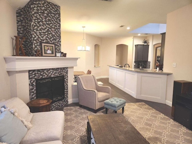 living room with a notable chandelier, recessed lighting, baseboards, and a tile fireplace