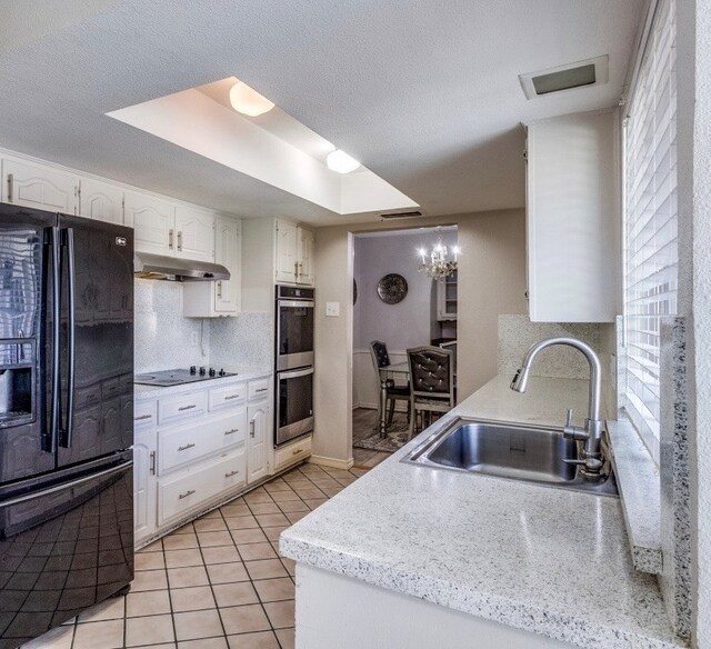 kitchen with a sink, decorative backsplash, black appliances, under cabinet range hood, and white cabinetry