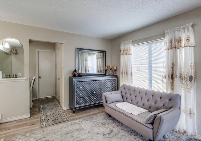 living area featuring wood finished floors, baseboards, and a textured ceiling