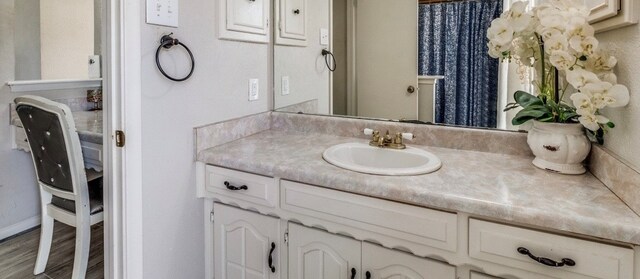 bathroom with vanity, wood finished floors, and baseboards