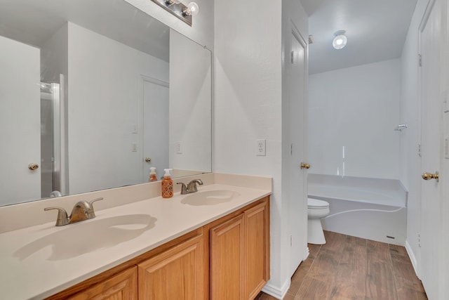 full bathroom featuring double vanity, wood finished floors, toilet, and a sink