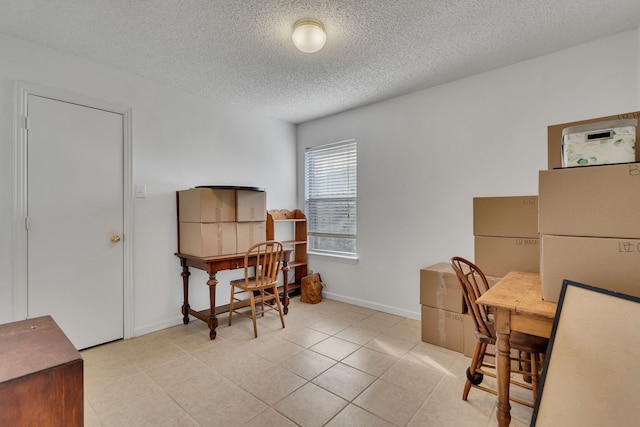 office space featuring light tile patterned flooring, baseboards, and a textured ceiling