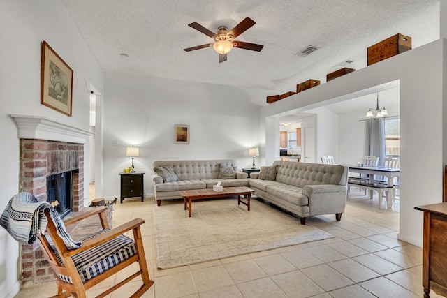 living area with a brick fireplace, light tile patterned floors, visible vents, and a textured ceiling