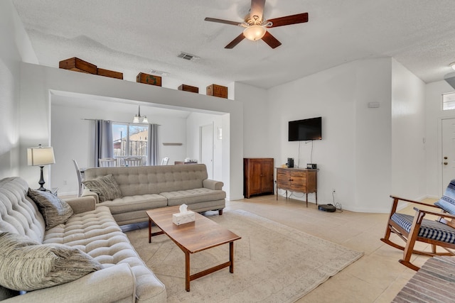 living area with a ceiling fan, baseboards, visible vents, light tile patterned flooring, and a textured ceiling