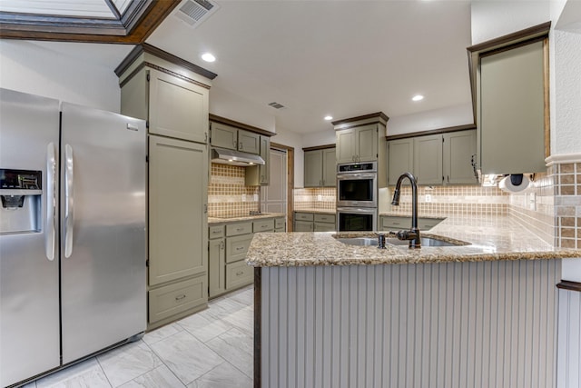 kitchen with visible vents, under cabinet range hood, a peninsula, stainless steel appliances, and a sink