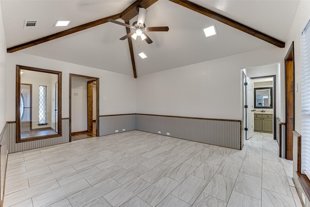 unfurnished room with visible vents, vaulted ceiling with beams, wainscoting, a ceiling fan, and a sink