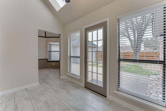 doorway with baseboards, high vaulted ceiling, marble finish floor, and a skylight