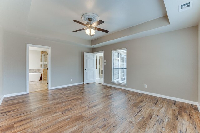 empty room featuring baseboards, a raised ceiling, and wood finished floors