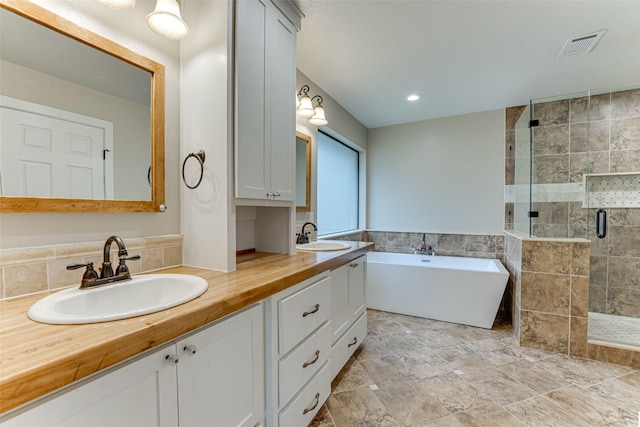 full bathroom with a sink, visible vents, a freestanding bath, and a shower stall