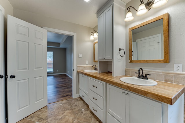 full bathroom featuring double vanity, baseboards, and a sink