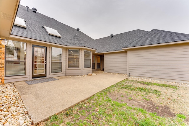 back of property with a patio and a shingled roof