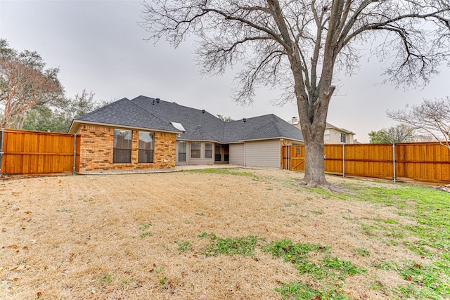 rear view of property featuring a patio area, brick siding, a lawn, and fence