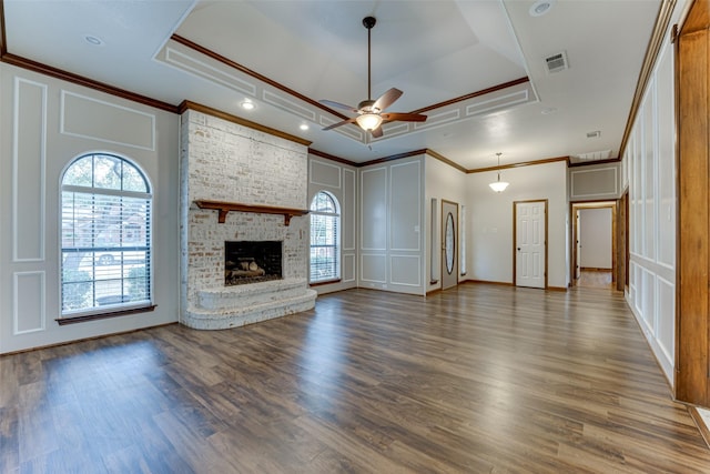 unfurnished living room featuring wood finished floors, a fireplace, ceiling fan, crown molding, and a raised ceiling