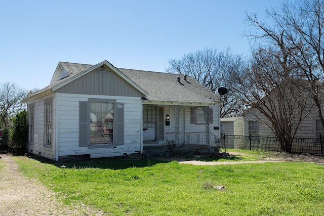 bungalow-style house with covered porch, roof with shingles, a front lawn, and fence