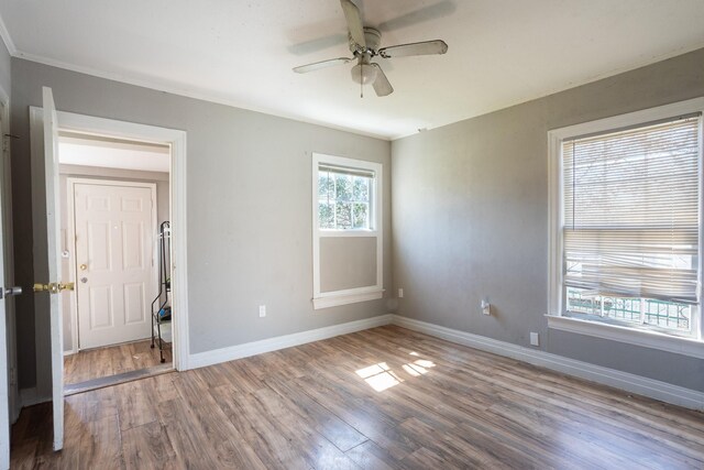 empty room featuring ceiling fan, baseboards, and wood finished floors