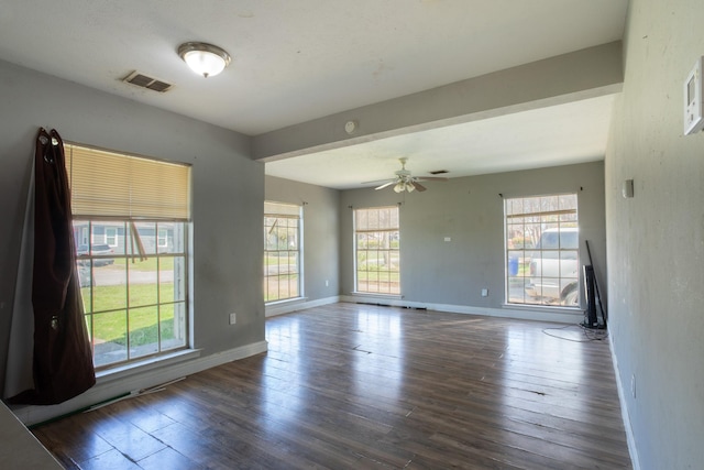 unfurnished room with a wealth of natural light, baseboards, visible vents, and wood-type flooring