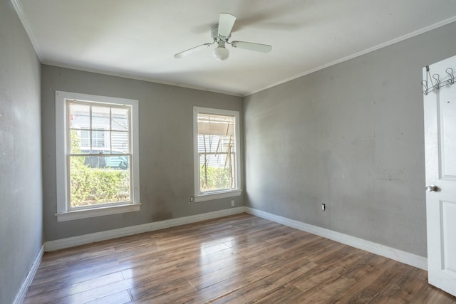 empty room featuring ceiling fan, crown molding, baseboards, and wood finished floors