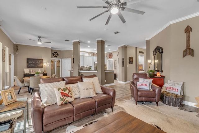 living room with visible vents, light wood finished floors, ornate columns, ceiling fan, and ornamental molding