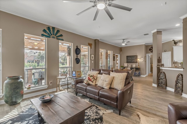 living room with a ceiling fan, visible vents, light wood finished floors, ornate columns, and ornamental molding