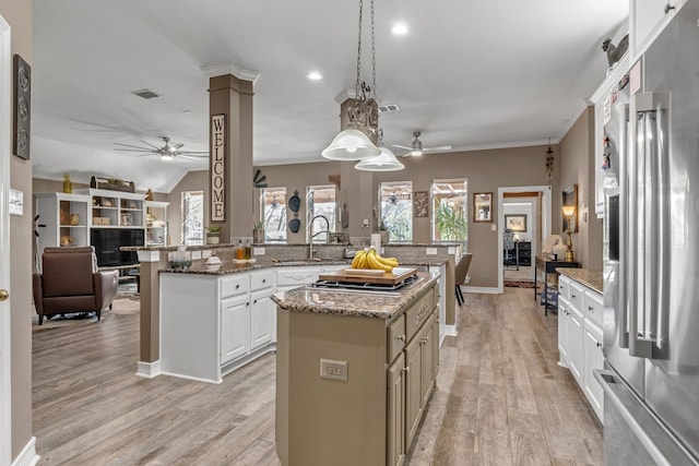 kitchen with decorative columns, a sink, a large island, stainless steel refrigerator with ice dispenser, and open floor plan