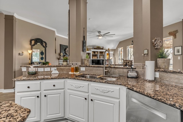 kitchen featuring a sink, dark stone countertops, white cabinets, and crown molding