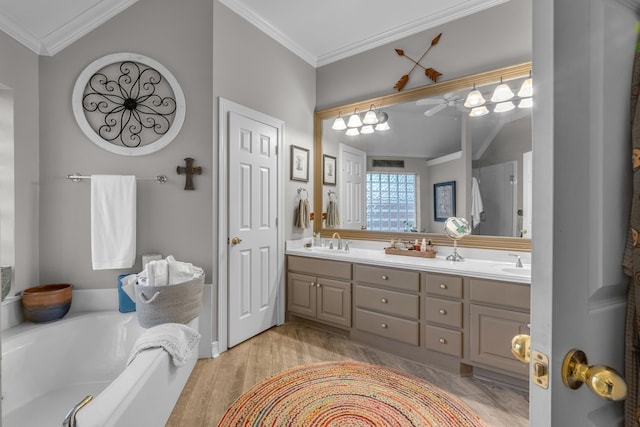 bathroom featuring a garden tub, ornamental molding, wood finished floors, and a sink