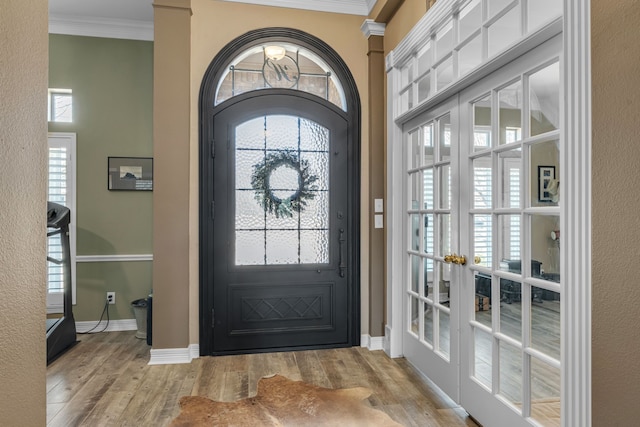 entryway with crown molding, wood finished floors, and baseboards