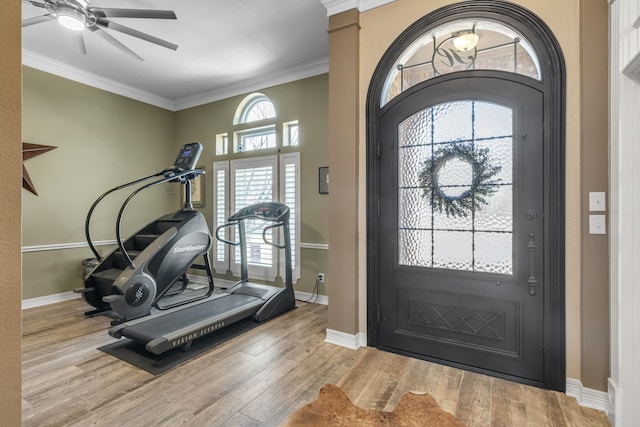 interior space with ceiling fan, baseboards, wood finished floors, and crown molding