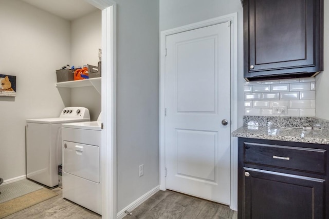 clothes washing area featuring washer and dryer, laundry area, baseboards, and light wood finished floors