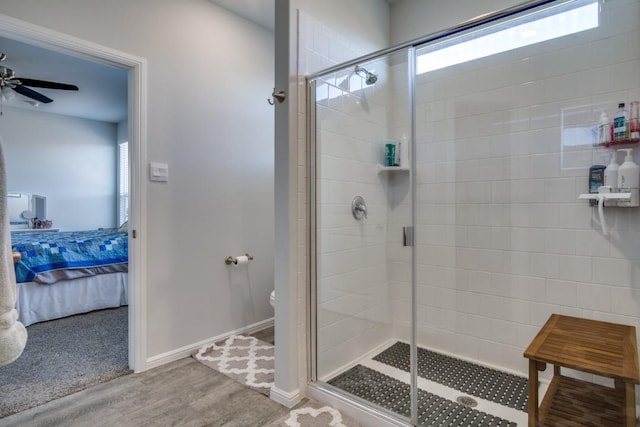 ensuite bathroom featuring toilet, ensuite bathroom, wood finished floors, a shower stall, and baseboards