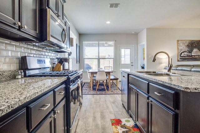 kitchen featuring light wood finished floors, visible vents, backsplash, appliances with stainless steel finishes, and a sink