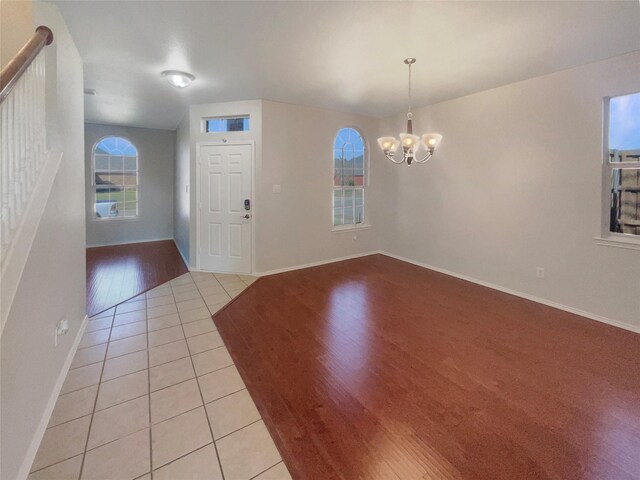 foyer entrance with baseboards, a notable chandelier, and light tile patterned flooring