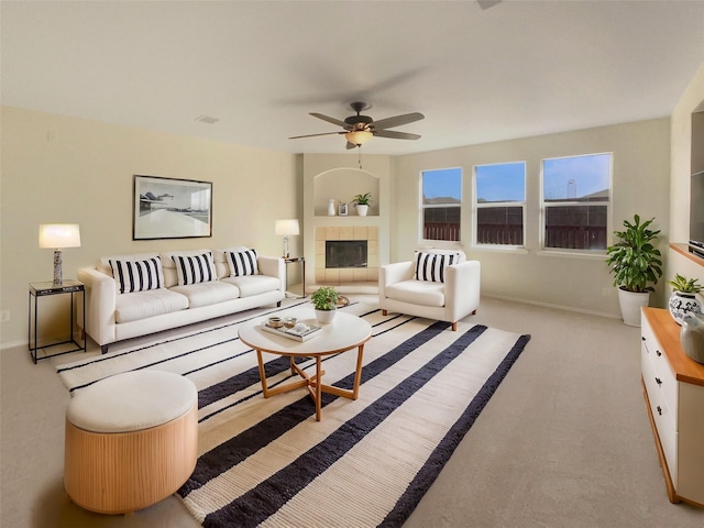 carpeted living area with baseboards, ceiling fan, and a fireplace