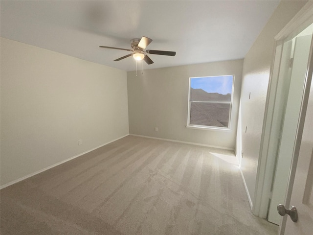 unfurnished room featuring baseboards, light colored carpet, and ceiling fan