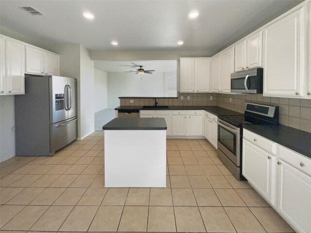 kitchen with light tile patterned flooring, decorative backsplash, stainless steel appliances, and dark countertops